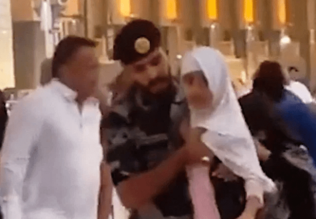 رجل أمن يحمي طفلة من عواصف مكة